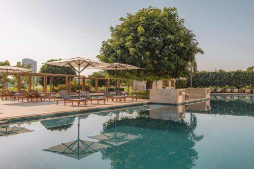 a pool with chairs and umbrellas and a tree at The Santa Maria, a Luxury Collection Hotel & Golf Resort, Panama City in Panama City