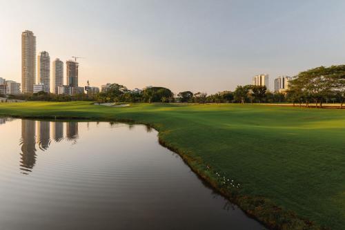 a golf course with a pond in front of a city at The Santa Maria, a Luxury Collection Hotel & Golf Resort, Panama City in Panama City