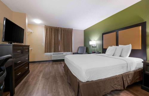 a hotel room with a bed and a flat screen tv at Extended Stay America Select Suites - St Louis - O' Fallon, IL in O'Fallon