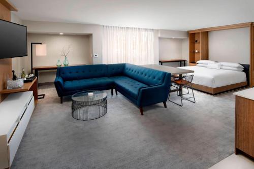 a living room with a blue couch and a bed at Delta Hotels by Marriott Seattle Everett in Everett