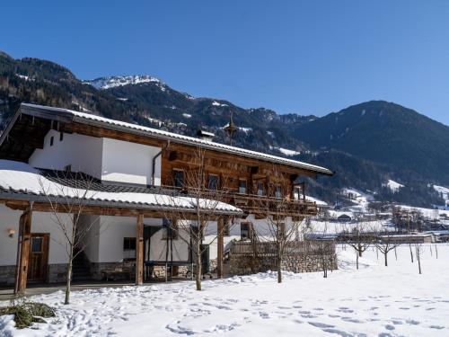 a building covered in snow with mountains in the background at Blick zum Mayrhofen in Ramsau im Zillertal