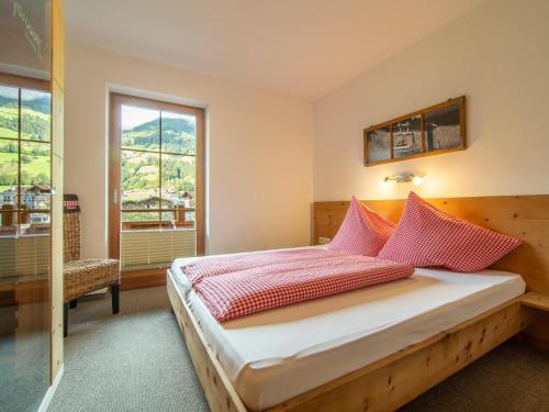 sypialnia z łóżkiem z czerwonymi poduszkami i oknem w obiekcie Blick zum Mayrhofen w mieście Ramsau im Zillertal