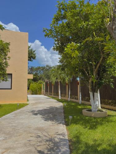 a sidewalk next to a building with trees and a fence at Villas Mandarina Bacalar in Bacalar