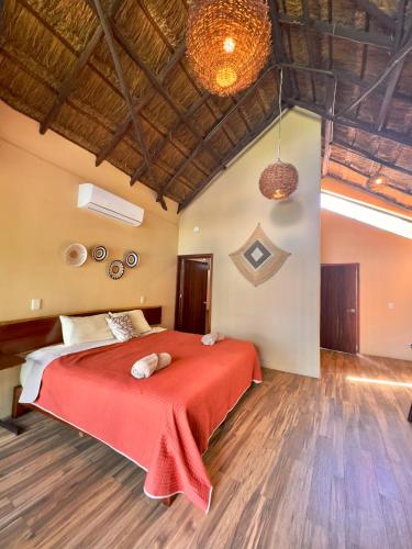 a bedroom with a large bed with a red blanket at Villas Mandarina Bacalar in Bacalar