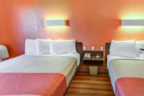 two beds in a room with orange walls at Motel 6-Portland, OR - Tigard West in Tigard