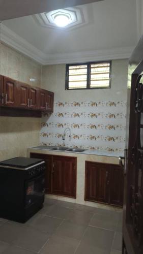 a kitchen with wooden cabinets and a window above a stove at Liberty Guesthouse in Abomey-Calavi
