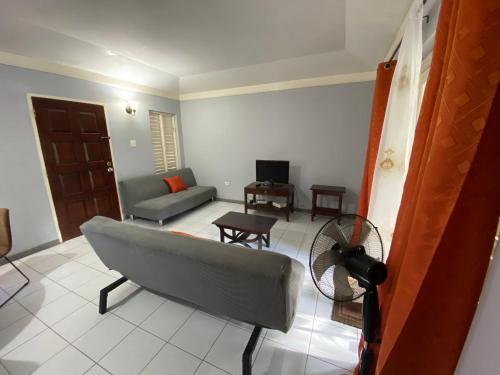 a living room with a couch and a fan at Finest Accommodation Renfrew Place Apt # 41 4--12 Renfrew Rd New Kgn in New Kingston