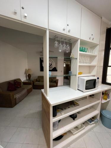 Una cocina con gabinetes blancos y una sala de estar. en Paraíso Condomínio Wembley Tênis G-302, en Ubatuba