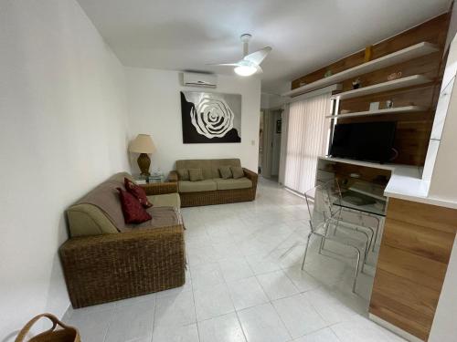 a living room with a couch and a television at Paraíso Condomínio Wembley Tênis G-302 in Ubatuba
