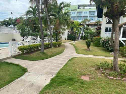 a walkway through a park with palm trees and a building at Finest Accommodation Renfrew Place Apt # 41 4--12 Renfrew Rd New Kgn in New Kingston