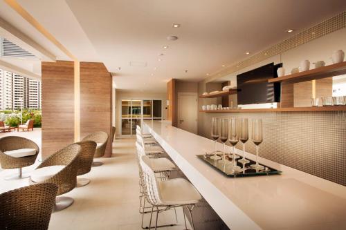 a lobby with a bar with chairs and tables at Loft Barra da Tijuca - Ilha Pura - Rock in Rio, Riocentro in Rio de Janeiro