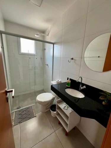 a bathroom with a sink and a toilet and a mirror at Apê 212 - Piscina, Churrasqueira, 2 Quartos a 600m da Orla Central in Ubatuba