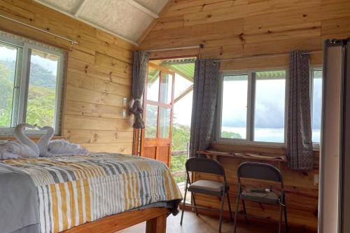 1 dormitorio con cama, ventanas y escritorio en 壮观景色的宁静木屋, en Santa Ana