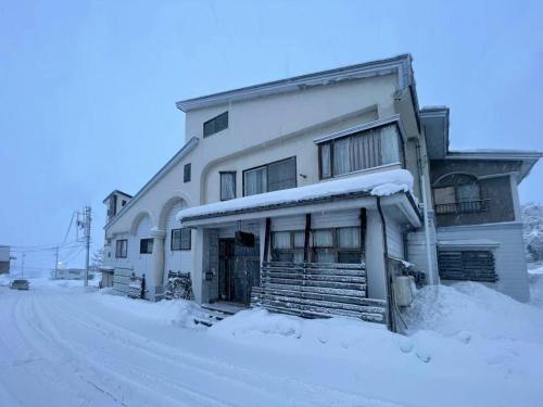 a building with snow on the side of it at Nozawa Onsen15M JapowPension粉雪館 in Iiyama