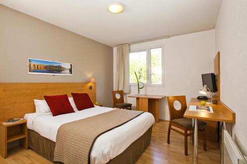 a hotel room with a large bed and a desk at Séjours & Affaires Toulouse de Brienne in Toulouse
