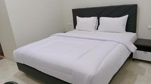a large bed with white sheets and a black headboard at GRAND KHALIFAH Guesthouse in Sumbawa Besar