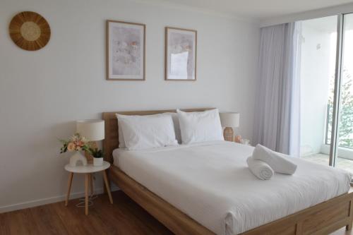 a bedroom with a large bed with white sheets and a window at Northwind Beachfront Apartments in Mooloolaba