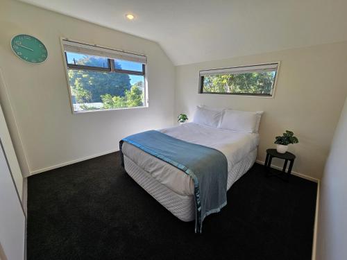 クライストチャーチにあるAzena Suites & Apartmentのベッドルーム1室(ベッド1台、壁掛け時計付)