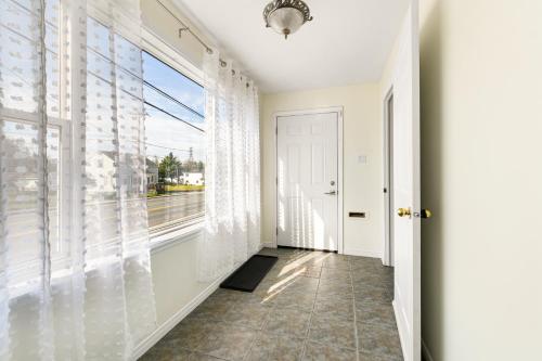 a hallway with a large window with white curtains at Spacious 4 bedrooms, 5 beds home - 3 Minutes to Downtown Moncton in Moncton