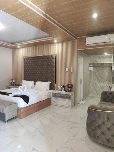 a bedroom with a large bed and two chairs at Nio Garden Hotel in Sumbawa Besar