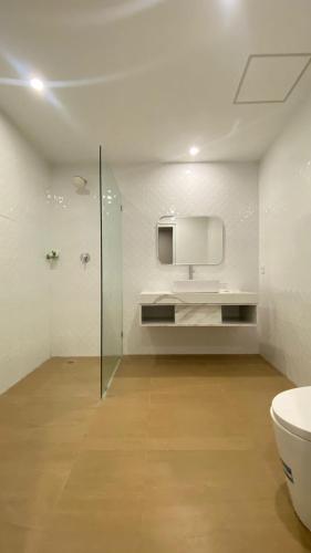 a white bathroom with a toilet and a sink at Nio Garden Hotel in Sumbawa Besar
