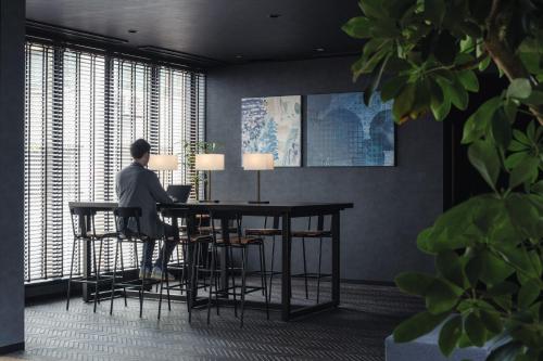 a man sitting at a table with a laptop at Nest Hotel Tokyo Yaesu in Tokyo