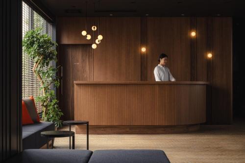 a man standing behind a counter in a lobby at Nest Hotel Tokyo Yaesu in Tokyo
