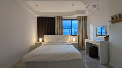 a bedroom with a bed with two lamps and a window at Pattaya Hagone Condotel in Pattaya South
