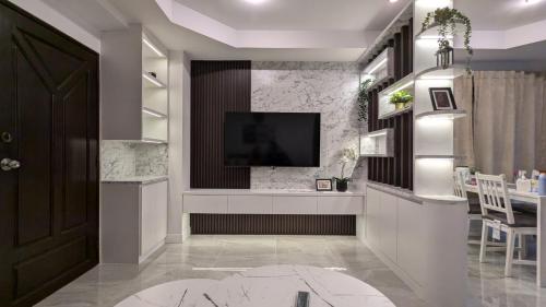 a living room with a television on a wall at Pattaya Hagone Condotel in Pattaya South