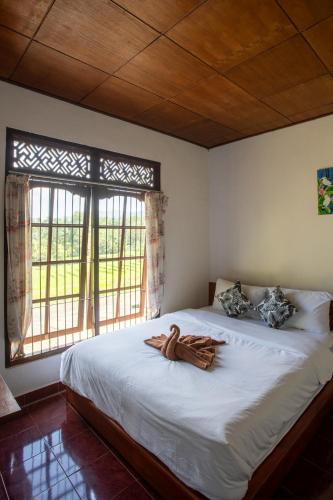 a bedroom with a large white bed with a window at Pondok Hari Baik in Balian