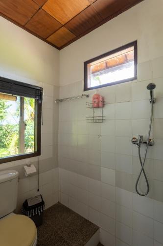 a bathroom with a toilet and a window and a shower at Pondok Hari Baik in Balian