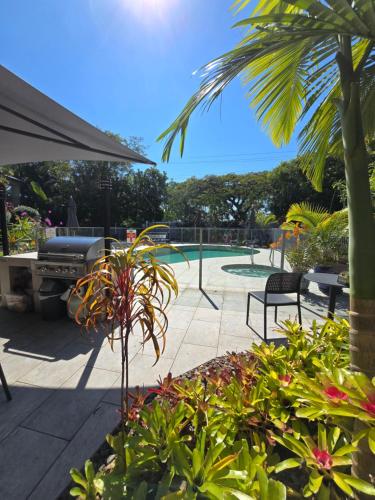 a patio with a pool and a grill and plants at Noosa River Retreat Holiday Apartments in Noosaville