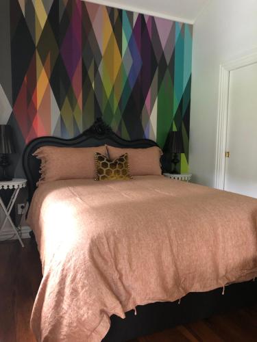 a bedroom with a bed with a colorful wall at The Wash-House historic Cottage Close to Hobbiton in Matamata