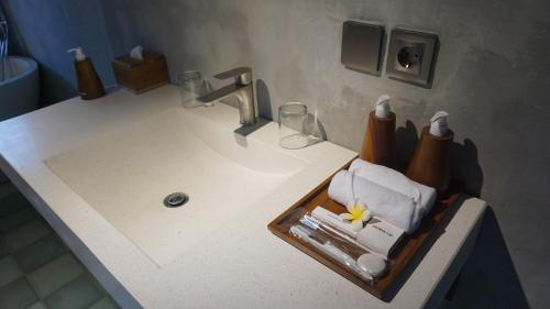 a bathroom sink with a tray of toiletries on it at Harmony Wooden Villas in Ubud