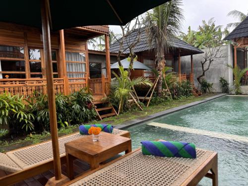 a resort with a pool and a table with an umbrella at Harmony Wooden Villas in Ubud