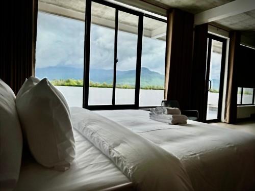 a bed with white sheets and pillows in a room with windows at STONE AGE Boutique in Kampot