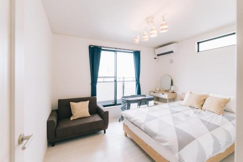 a bedroom with a bed and a chair and a window at 惠 - Megumi Okinawa in Tokeshi