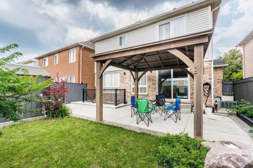 a covered patio with chairs and tables in a yard at Garden 2 BR Apt - Free Parking Wifi Laundry Workstation in Brampton