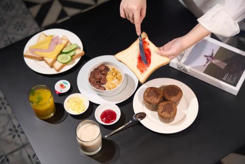 uma pessoa cortando um sanduíche em uma mesa com comida em M Village Hotel Tôn Thất Đạm em Cidade de Ho Chi Minh