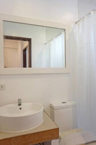 a bathroom with a sink and a mirror and a toilet at Two Bedroom Affordable Beach Front House in Boracay