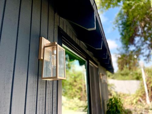 a light on the side of a house with a window at Sunny Days Tiny House with private entrance, pool and view in West Covina