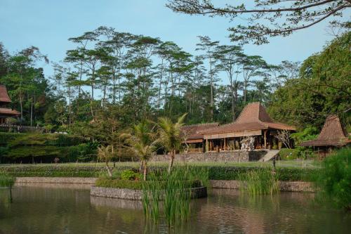 a building next to a pond in a park at d'Temanggung Villa in Temanggung