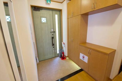 a kitchen with a door and a red fire extinguisher at AK apartment 2F in Jima