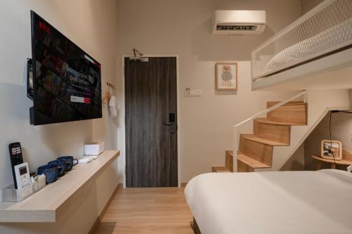 a bedroom with a bed and a tv and stairs at La Vie Hotel Juru in Simpang Ampat