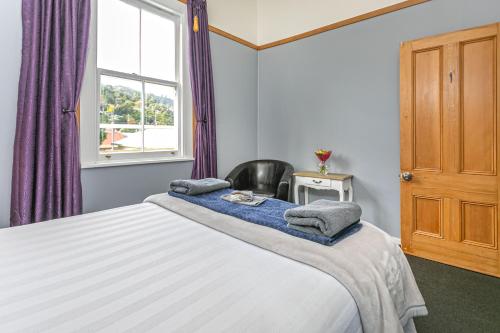 a bedroom with a bed with a chair and a window at Lady Bowen Bed & Breakfast in Thames