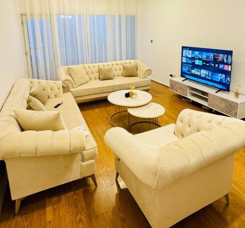 a living room with white furniture and a flat screen tv at Spacious 3-Bedroom Apartment near Al Khan Beach in Al Khān