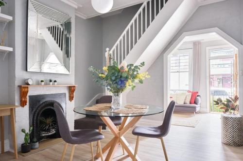 a dining room with a table and chairs and a fireplace at Redfern Classic Terrace - Parking and Balcony in Sydney