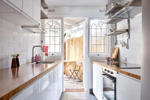 a kitchen with white walls and a counter with a sink at Redfern Classic Terrace - Parking and Balcony in Sydney