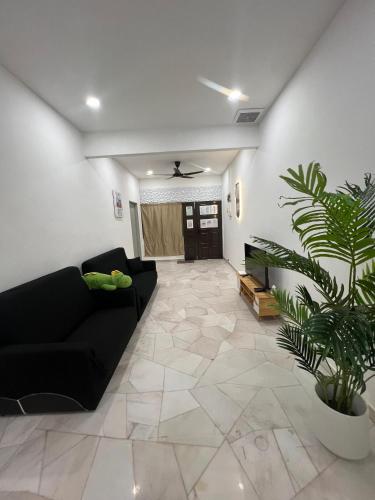 a living room with a black couch and a plant at 9pax -Taman Bagan Butterworth -Budget Homestay in Butterworth