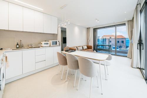 a kitchen with white cabinets and a table and chairs at Ddosi Aewol Pool Villa in Jeju